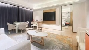 Una habitación de hotel moderna con zona de comedor, una cama grande y vistas a las montañas.