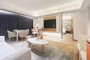 Una habitación de hotel moderna con zona de comedor, una cama grande y vistas a las montañas.