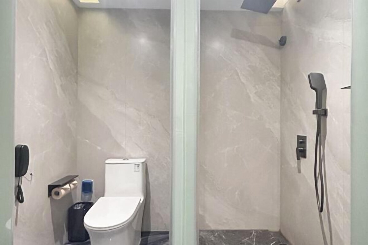 Ein kleines, abgeschlossenes Badezimmer mit Toilette, Dusche und Telefon.