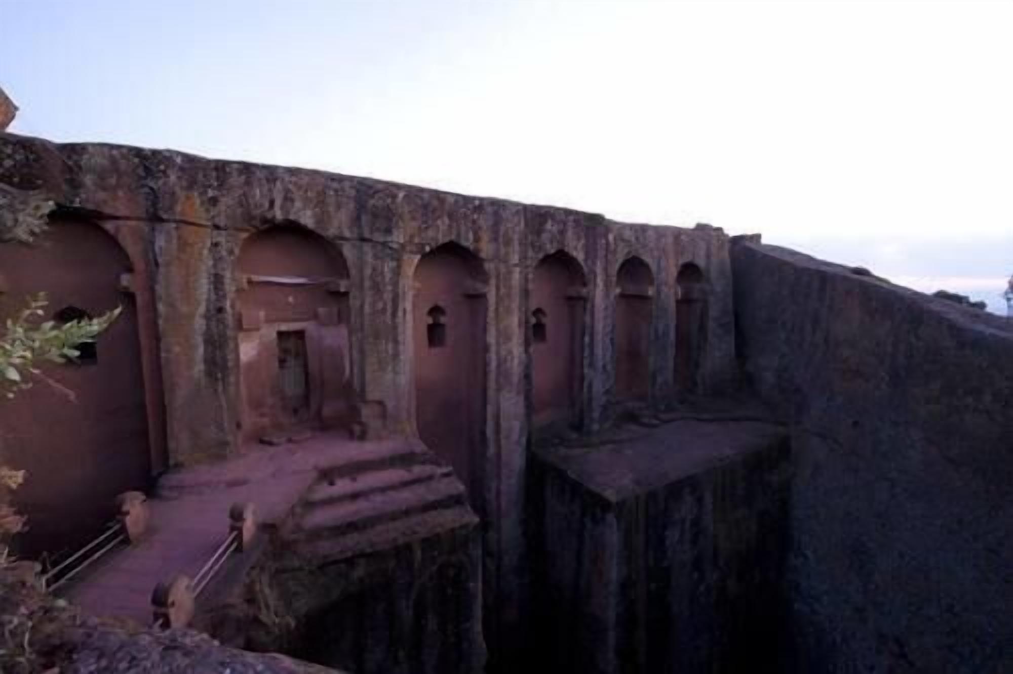 A large, ancient stone structure with multiple arched doorways and a central staircase leading up to a higher level.