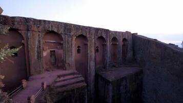 A large, ancient stone structure with multiple arched doorways and a central staircase leading up to a higher level.