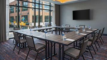 A conference room with a long table, chairs, water bottles, and a TV on the wall.
