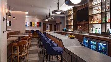 Un espace bar doté d’un long comptoir, de tabourets de bar et d’une variété de bouteilles et de verres.