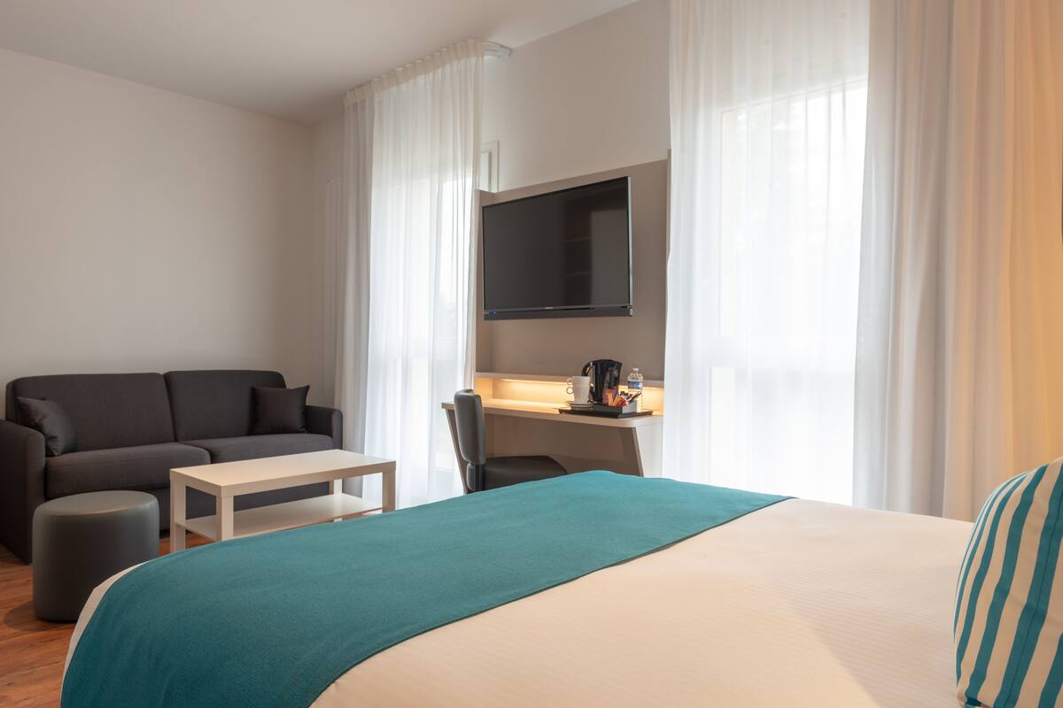 Une chambre d’hôtel moderne équipée d’un lit, d’un canapé, d’un bureau et d’une télévision.