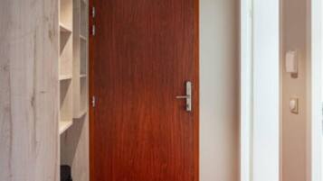 Un pasillo con un armario de madera, una alfombra roja y una puerta de madera.