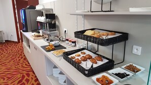 Una mesa de buffet con diversos alimentos, incluyendo pasteles y salsas.
