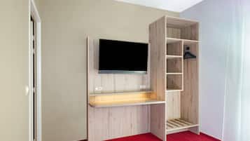 A room with a built-in TV shelf, a red carpet, and a wooden wardrobe with multiple compartments.