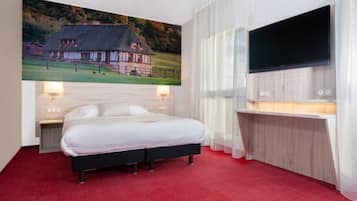 Habitación de hotel con una cama grande, un escritorio, un televisor de pantalla plana y un cuadro de una casa en la pared.