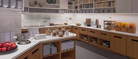 A modern kitchen with white cabinets, a breakfast bar, and various food items.