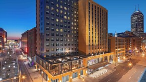 Un hôtel moderne, doté d’une enseigne bien visible, de plusieurs étages et d’un espace extérieur couvert aménagé avec des sièges.