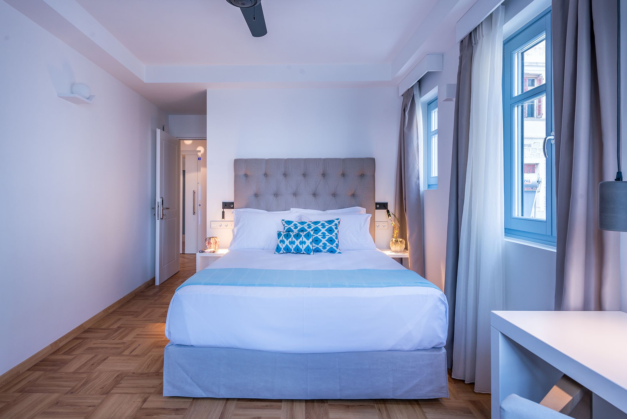 Ein modernes Hotelzimmer mit einem großen Bett, einem Nachttisch und einem Fenster mit Vorhängen.