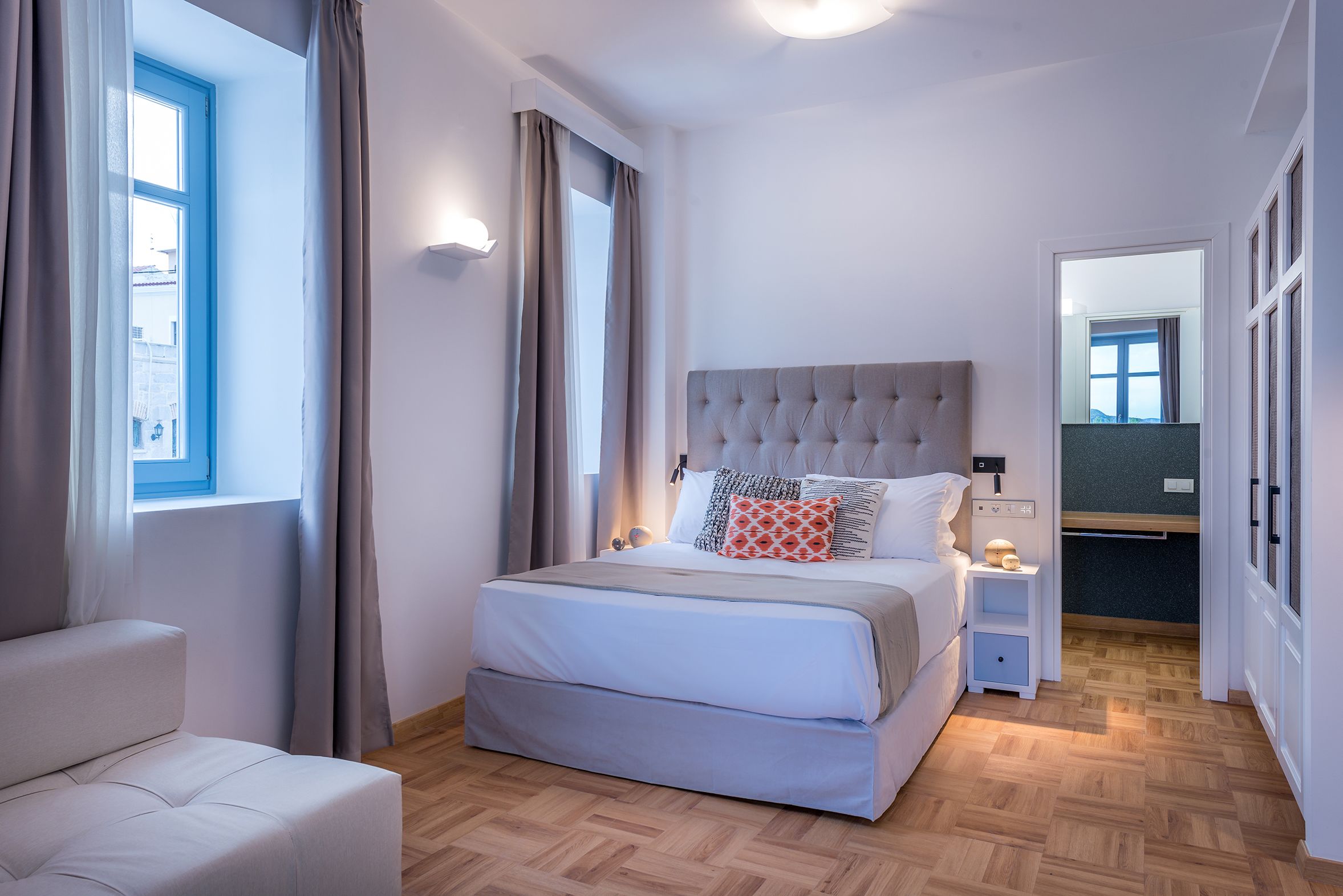 A modern bedroom with a large bed, bedside tables, and a view of the outside.