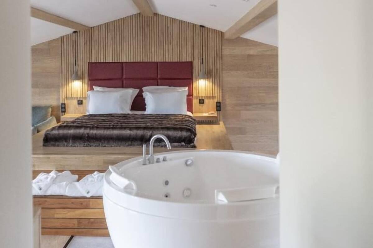 Un dormitorio moderno con una cama grande, techo de madera y baño separado con bañera.