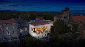 Ein modernes Haus mit Natursteinfassade, großen Fenstern und Blick auf die umliegende Landschaft.