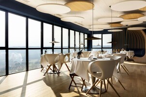 Un comedor moderno con ventanas amplias, focos redondos en el techo y vajilla blanca.