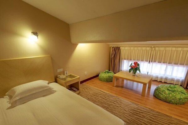 A hotel room with a bed, bedside table, lamp, window with curtains, and a small table with a vase. - Yuanzheng Shennong Hotel (Hangzhou)