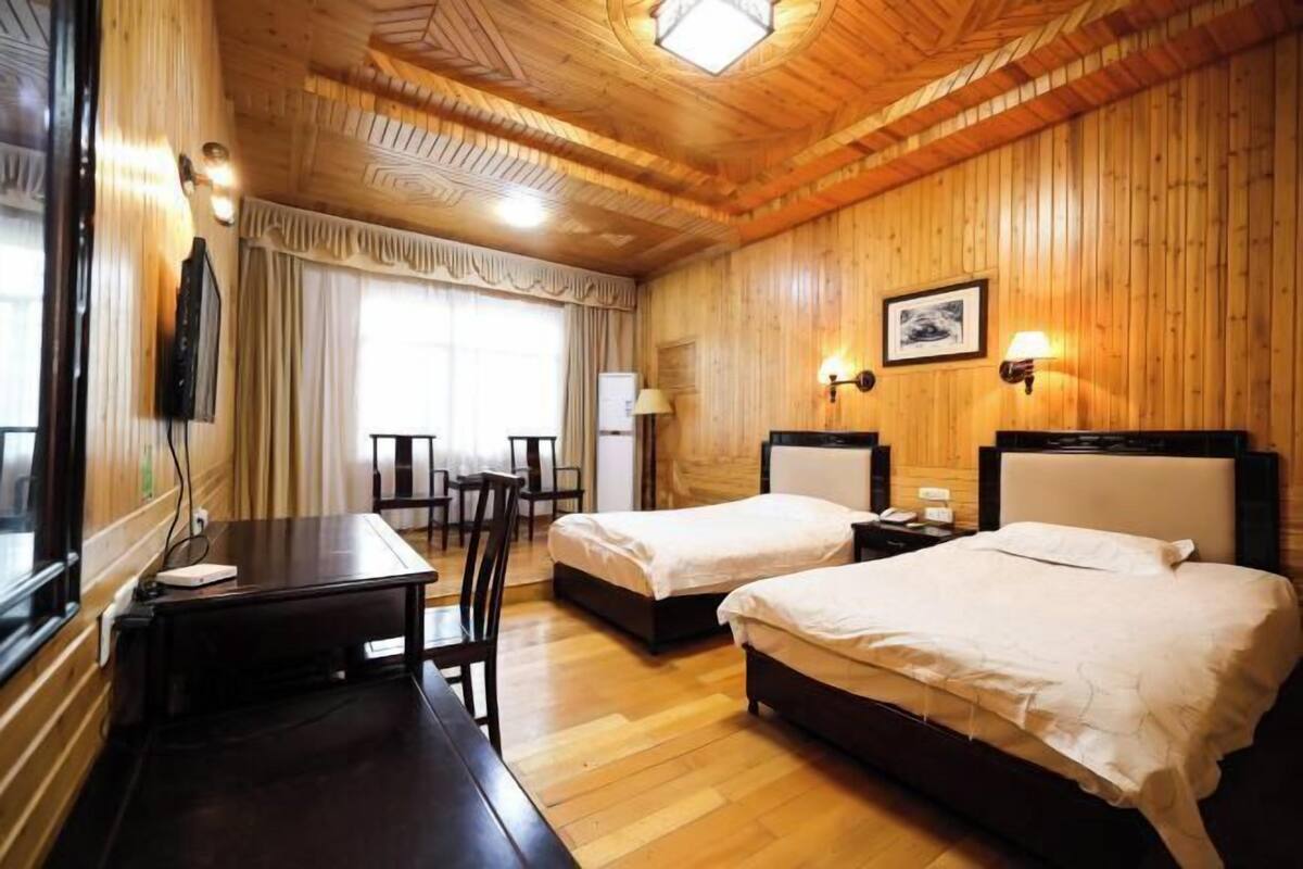 A wooden-paneled room with two beds, a desk, and a chair.