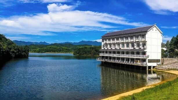 A large, multi-story building with a flat roof, situated on a riverbank. - Ningguo Wooden Villa of the World (Ningguo)
