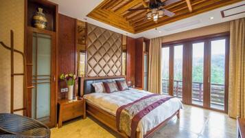 A spacious bedroom with a large bed, wooden ceiling, and a balcony with a view.