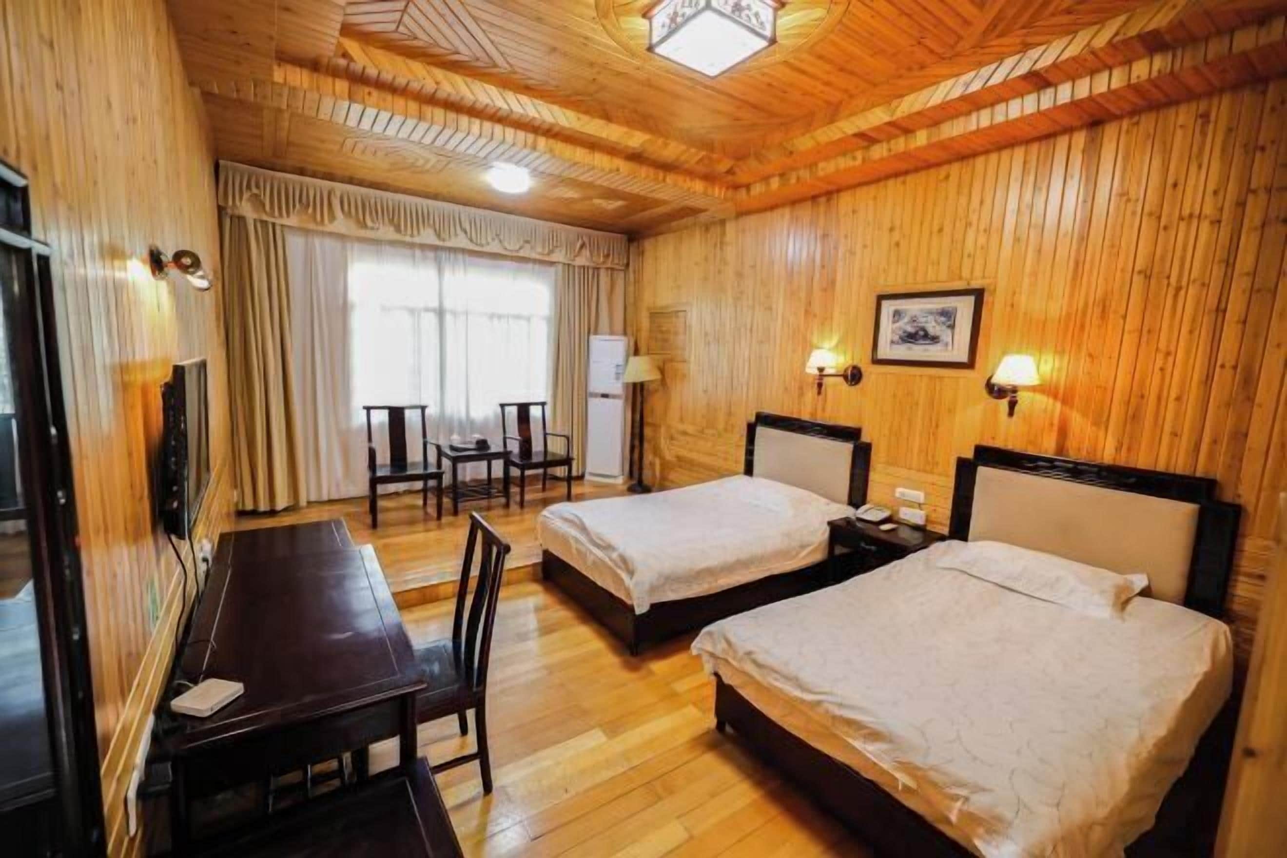 Ein Zimmer mit Holzwänden, zwei Betten, einem Schreibtisch und einem Stuhl.