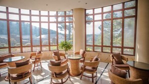 A spacious room with large windows, wicker furniture, and a central glass table. - Ningguo Wooden Villa of the World (Ningguo)