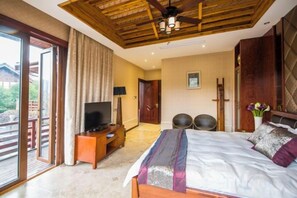 A bedroom with a bed, a television, a ceiling fan, and a view of the outdoors. - Ningguo Wooden Villa of the World (Ningguo)