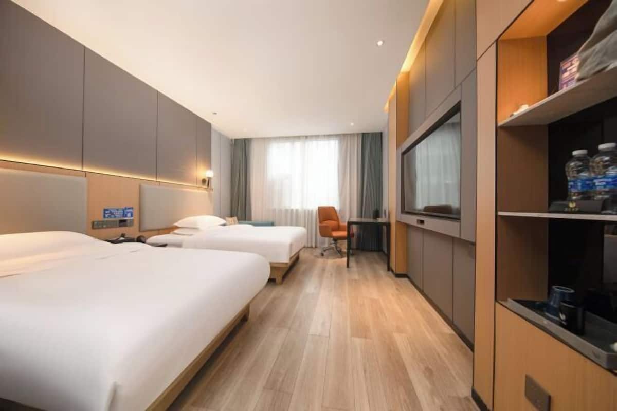 A hotel room with two beds, a desk, and a chair.