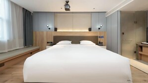 Une chambre d’hôtel moderne avec un grand lit, des tables de chevet, un téléviseur intégré et une armoire.