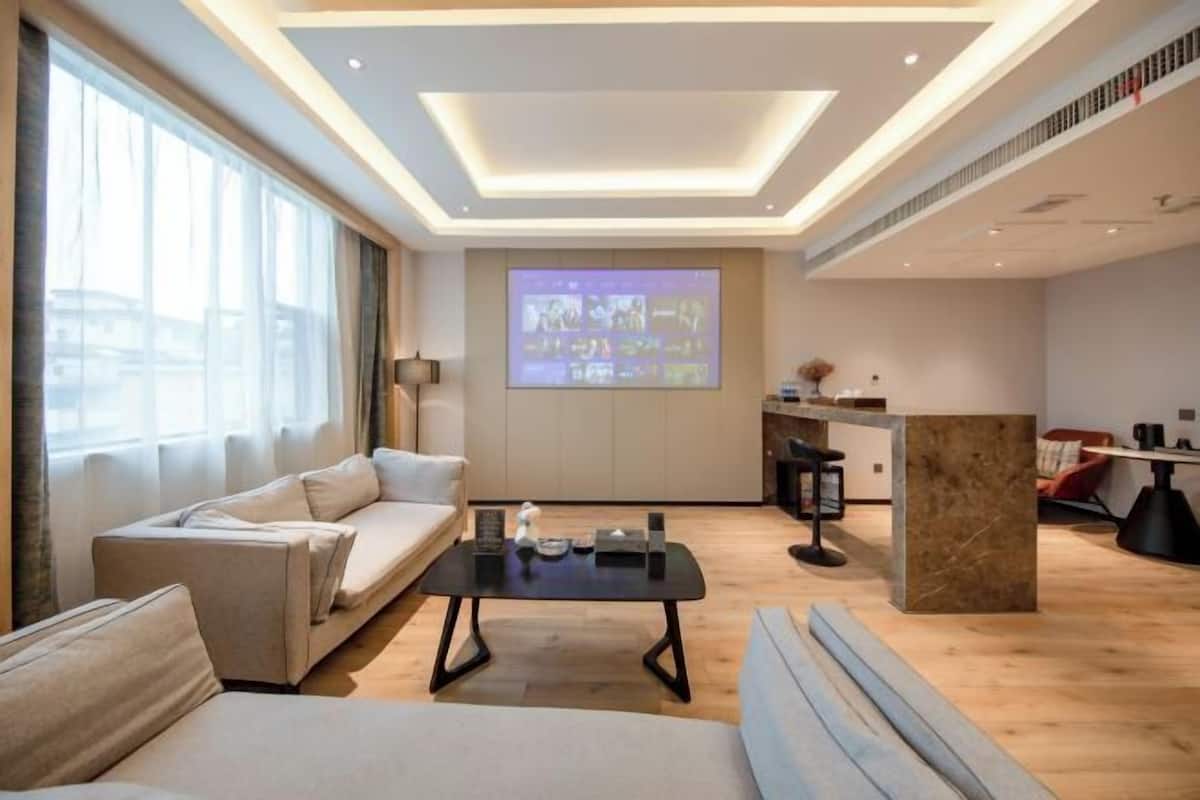 A modern living room with a sofa, coffee table, and a projection screen.