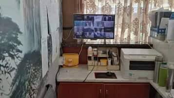 Un pequeño espacio de oficina con un monitor de computadora, una impresora y diversos útiles de escritorio sobre un escritorio.