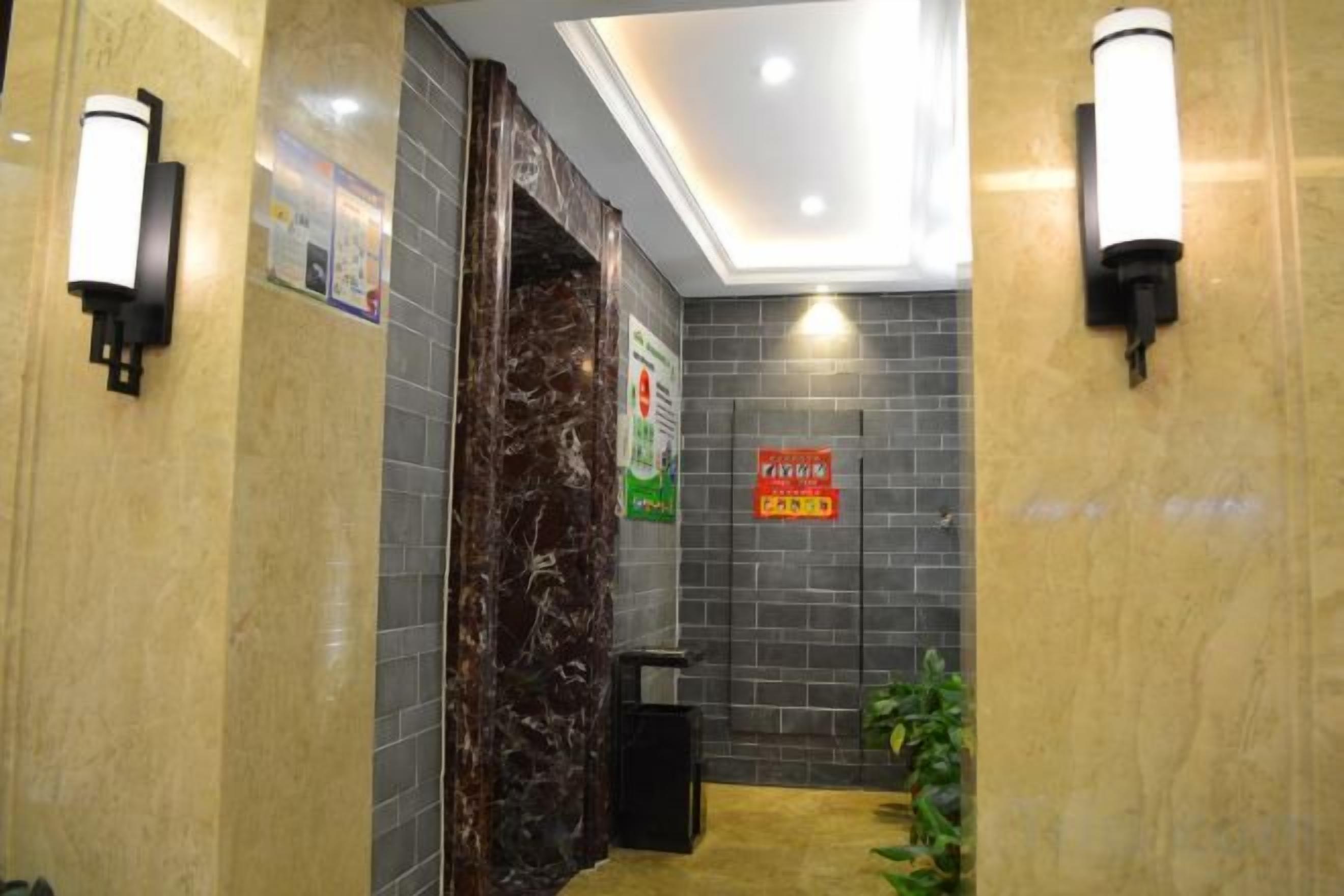 A hotel lobby with marble walls, a reception desk, and a trash bin.