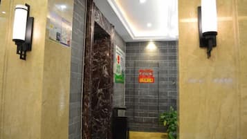A hotel lobby with marble walls, a reception desk, and a trash bin.