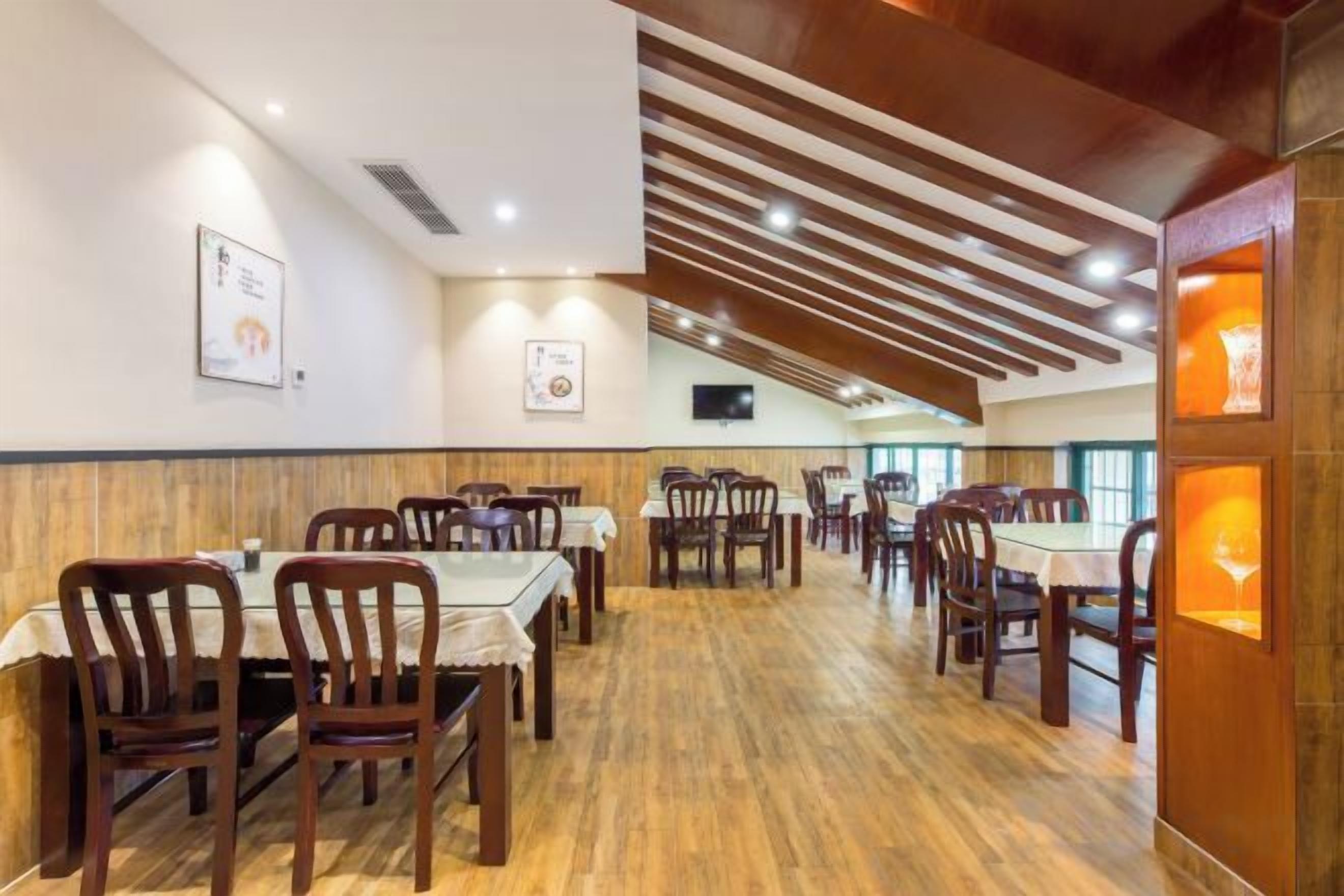 Un restaurante con suelo de madera, mesas con manteles blancos y sillas.
