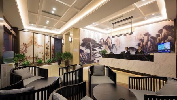 A hotel lobby with a reception desk, seating area, and decorative wall art. - Junlin Four Seasons Hotel (ZHEJIANG)