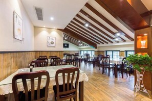A restaurant with wooden flooring, tables with lace tablecloths, and chairs. - Junlin Four Seasons Hotel (ZHEJIANG)