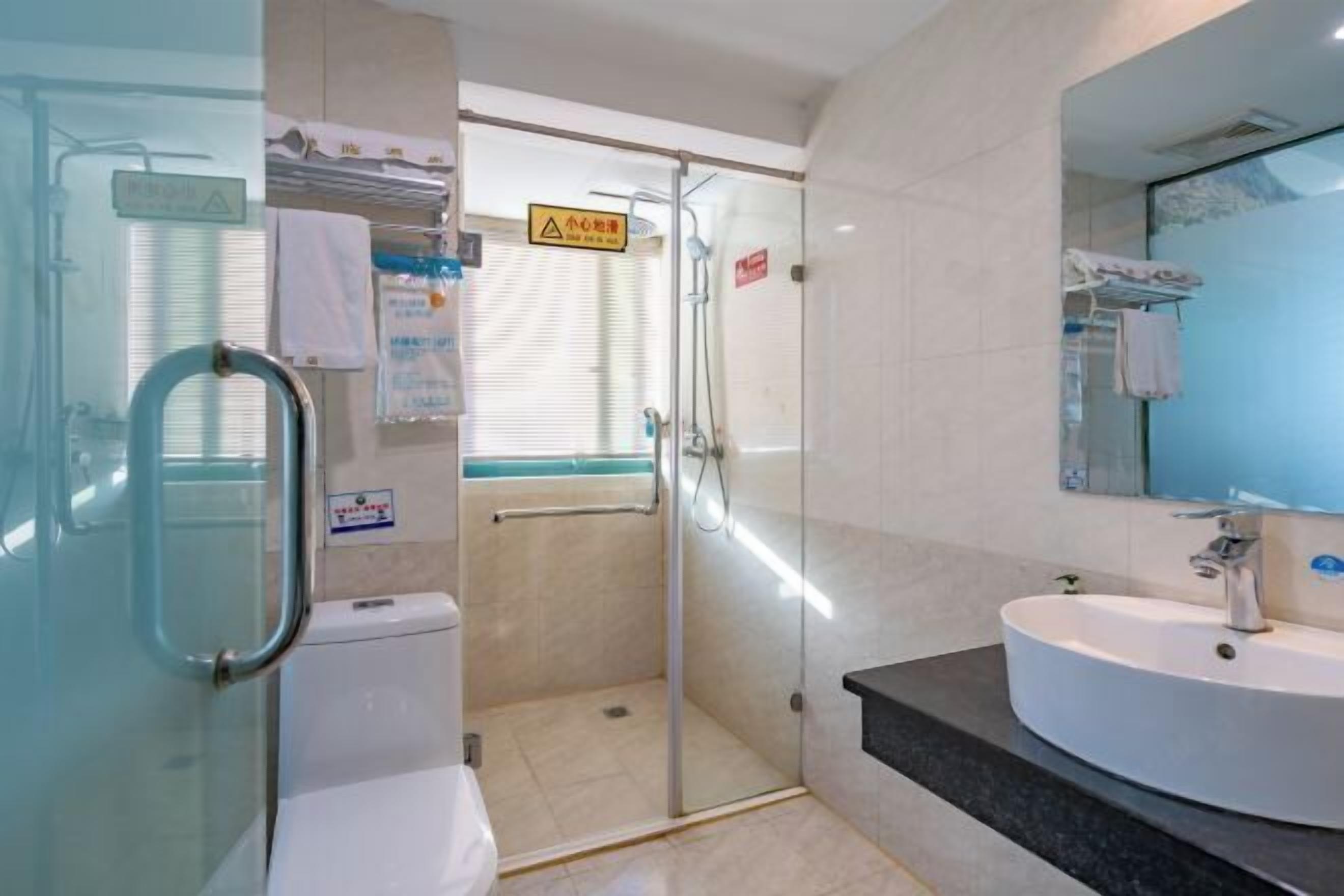 Un baño moderno con cabina de ducha de vidrio, un lavabo blanco y un espejo.