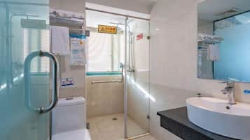 Un baño moderno con cabina de ducha de vidrio, un lavabo blanco y un espejo.