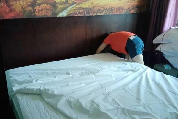 Un lit avec une couvre-lit blanche et une tête de lit adossée à un mur.