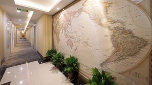 A hotel corridor with a large world map on the wall, potted plants, and a marble floor. - Junlin Four Seasons Hotel (ZHEJIANG)