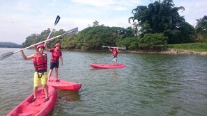 Three people on a river in red kayaks, wearing life jackets and holding paddles. - Hosteria Piedra De Vapor (Puerto Quito)