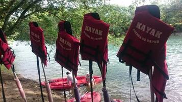 Plusieurs kayaks rouges étaient alignés au bord d’une étendue d’eau, et une personne se trouvait dans un kayak à proximité.