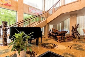 A grand lobby with a piano, a staircase, and a large window overlooking greenery. - ZheShang ShiMao Yulong Hotel (Haining)