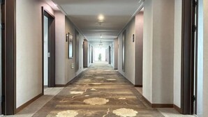 Un pasillo largo y estrecho con alfombra estampada y puertas a ambos lados.