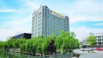 A modern hotel with a multi-story structure, a river in front, and a pedestrian walkway.