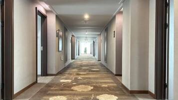 A hotel corridor with doors on both sides, a patterned carpet, and a ceiling light.