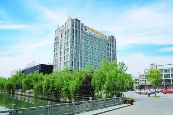 Un hotel moderno con fachada de vidrio, situado junto a un canal con abundante vegetación.
