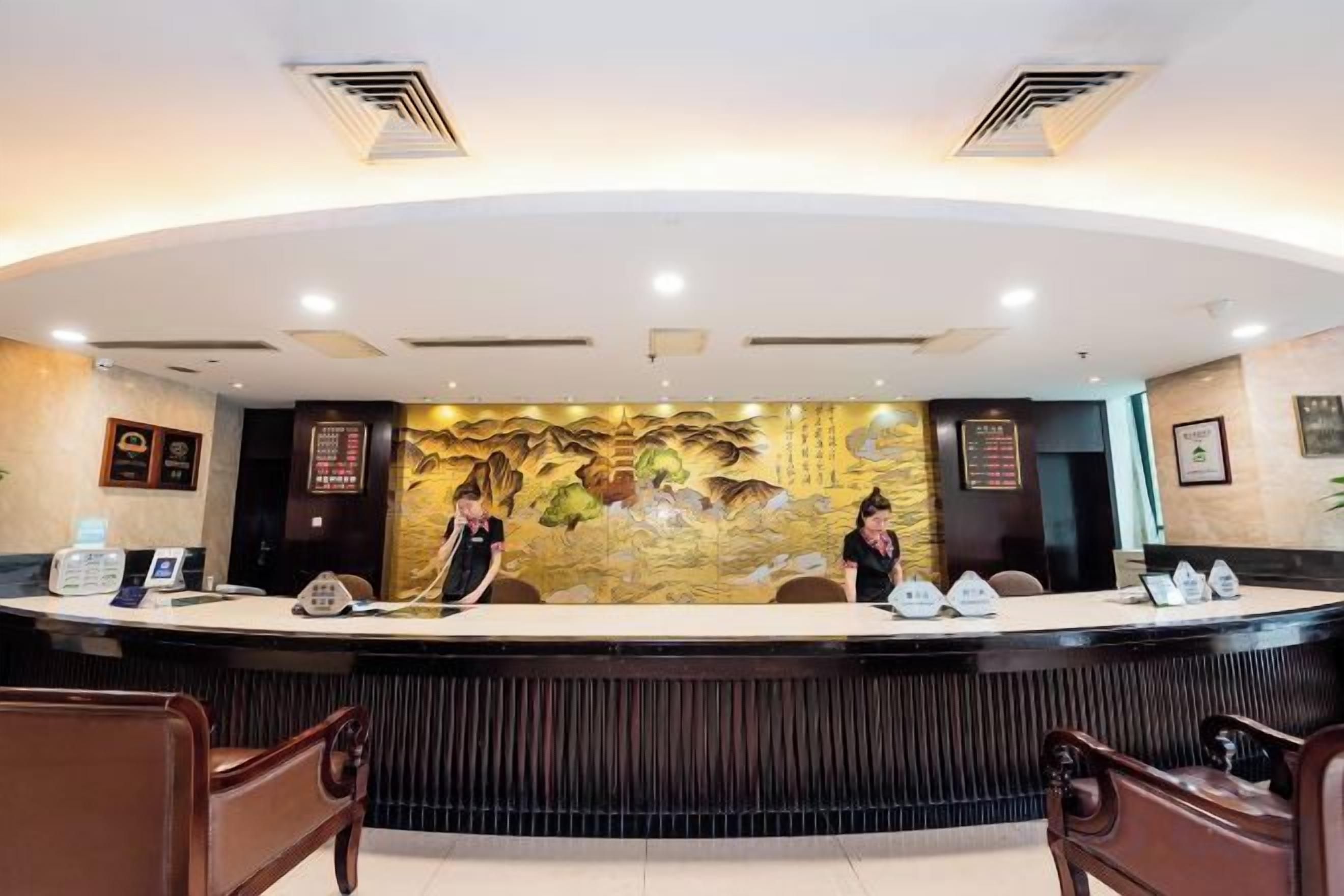 A reception desk with a mural, two receptionists, and a seating area with wooden chairs.
