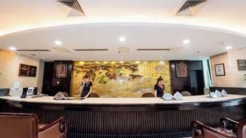 A reception desk with a mural, two receptionists, and a seating area with wooden chairs.