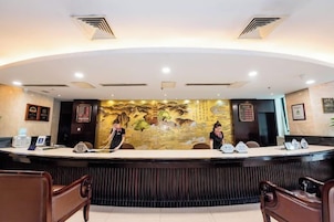 A reception desk with a mural, two receptionists, and a seating area with wooden chairs.