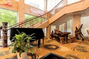 Un vestíbulo con un piano de cola, una escalera y un amplio ventanal con vistas a zonas verdes.